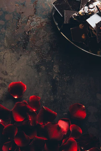 Beautiful red rose petals and pieces of gourmet chocolate with nuts — Stock Photo