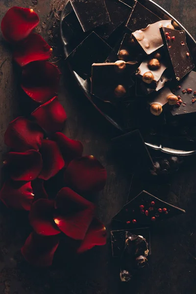 Top view of beautiful red rose petals and pieces of gourmet chocolate with nuts — Stock Photo