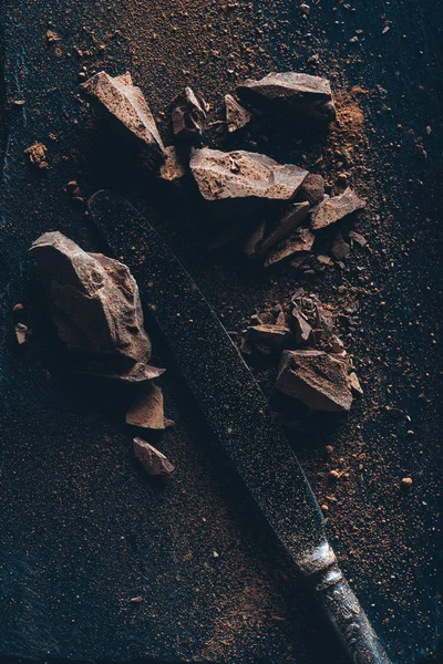 Vintage Messer, Schokoladenstücke und Kakaopulver auf dunkler Oberfläche — Stockfoto