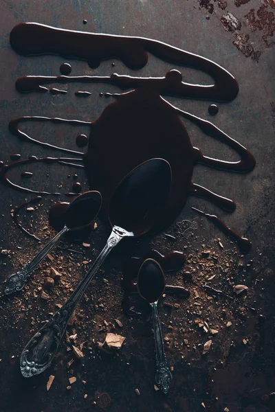 Top view of vintage spoons and delicious melted chocolate on dark surface — Stock Photo