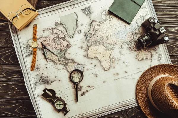 Flat lay with straw hat, map, magnifying glass, compass and retro photo camera on dark wooden tabletop — Stock Photo