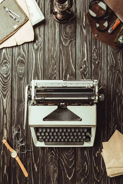 Flat lay with typing machine, envelopes, eyeglasses, bag with magnifying glasses and pocket knife on dark wooden surface — Stock Photo