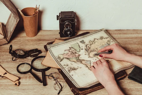 Foto recortada de mujer en la mesa con mapa, lupas, anteojos y cámara fotográfica retro - foto de stock