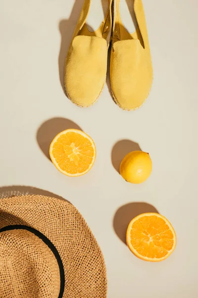 Top view of straw hat, lemon, orange slices and yellow stylish espadrilles — Stock Photo