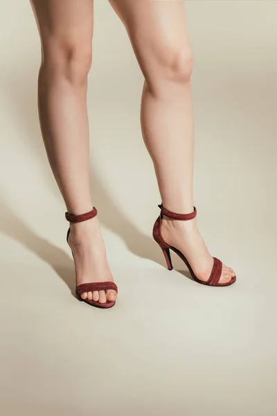 Обрезанное изображение женских ног в сандалиях на высоком каблуке на белом фоне — стоковое фото
