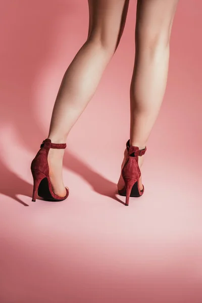 Vue arrière des jambes de la femme dans des sandales à talons hauts élégantes sur fond rose — Photo de stock