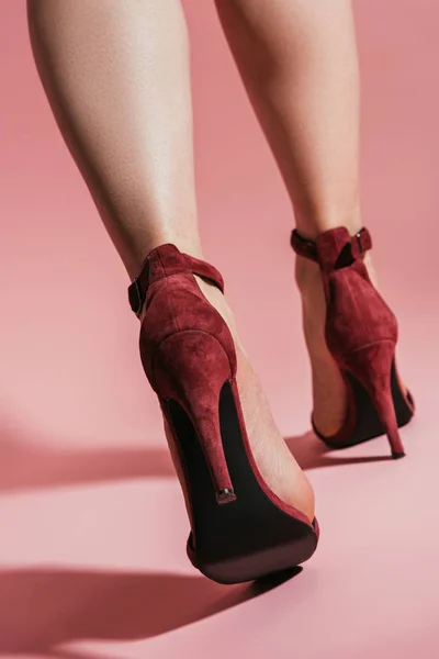 Vista basso angolo di piedi donna in eleganti sandali tacco alto su sfondo rosa — Foto stock
