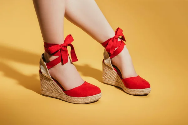 Image recadrée de pieds de femme dans des sandales de plate-forme élégantes sur fond jaune — Photo de stock