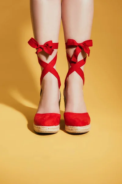 Image recadrée de pieds de femme dans des sandales de plate-forme élégantes sur fond jaune — Photo de stock