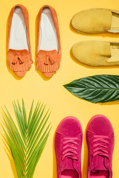 Vista superior de folhas tropicais e sapatos femininos elegantes no fundo amarelo — Fotografia de Stock
