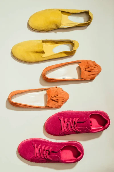 Vista dall'alto di eleganti scarpe da ginnastica femminili, pantofole e espadrillas poste in fila isolate su sfondo bianco — Foto stock