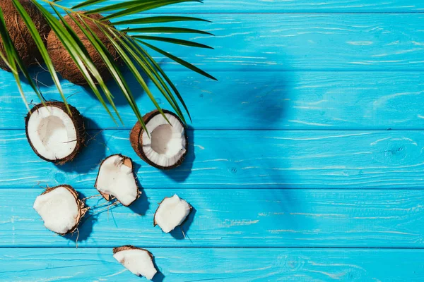 Vista superior de cocos y hojas de palma verde sobre superficie de madera turquesa - foto de stock