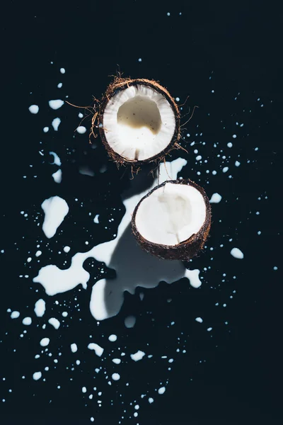 Top view of halved organic coconut and coconut milk on black — Stock Photo