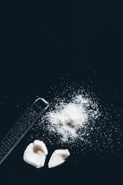 Top view of gourmet natural coconut shavings and grater on black — Stock Photo