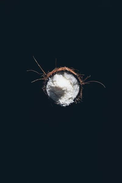 Top view of half of coconut with tasty healthy shavings isolated on black — Stock Photo