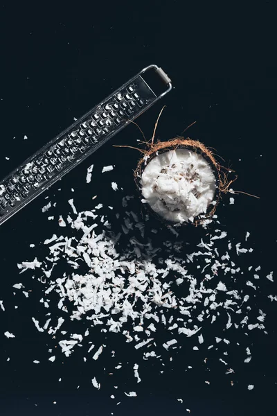 Close-up view of coconut, shavings and grater on black — Stock Photo