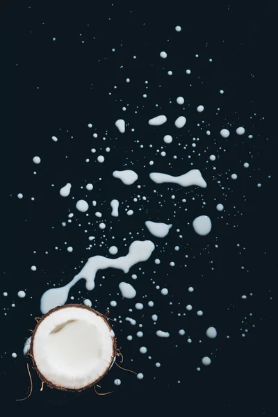 Top view of half of coconut and fresh coconut milk on black — Stock Photo