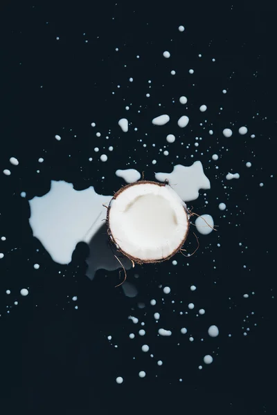 Half of coconut and fresh organic coconut milk on black — Stock Photo