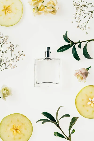 Вид зверху пляшки парфумів в оточенні квітів і шматочків яблука ізольовані на білому — стокове фото