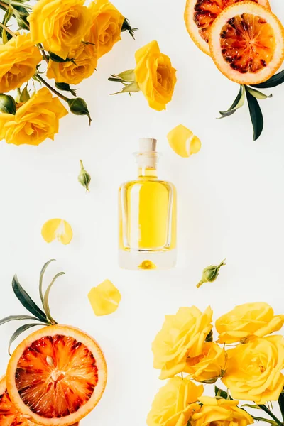 Top view of bottle of perfume with beautiful flowers around on white — Stock Photo