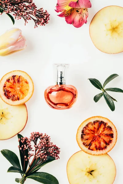 Vue du dessus du flacon de parfum entouré de fruits et de fleurs sur blanc — Photo de stock