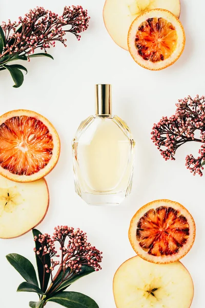 Vue du dessus du flacon de parfum en verre entouré de fruits et de fleurs isolés sur blanc — Photo de stock