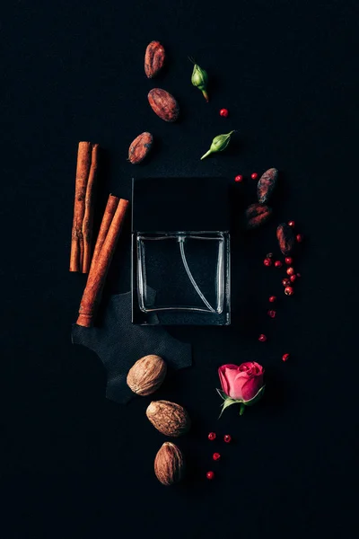 Vue du dessus du flacon de parfum entouré d'épices aromatiques sur noir — Photo de stock