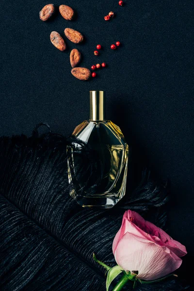 Top view of bottle of perfume with rose bud and spices on black — Stock Photo