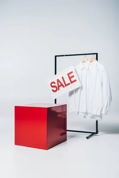 Cubo rojo, camisas en perchas y letrero de venta, concepto de venta de verano - foto de stock