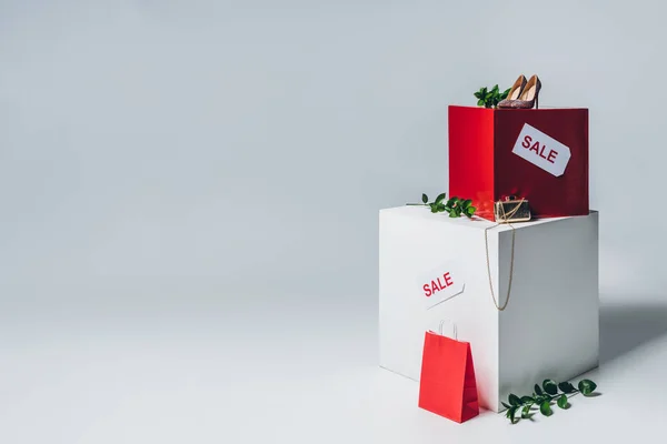 Twigs with green leaves, high heels and sale signs on cubes, summer sale concept — Stock Photo
