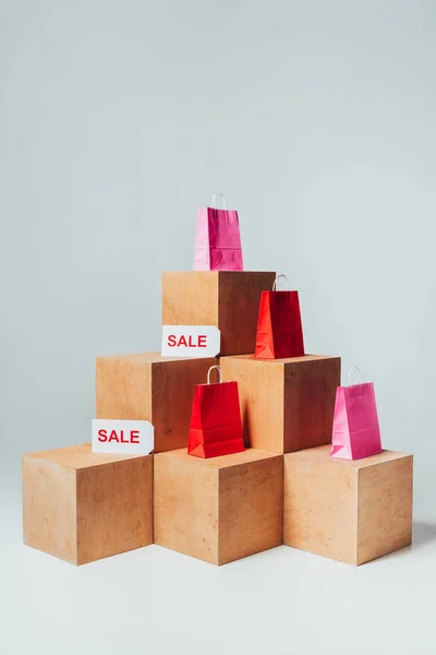 Red and pink shopping bags with sale signs on wooden cubes, summer sale concept — Stock Photo