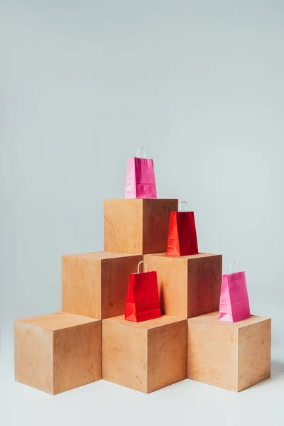 Bolsas de compras rojas y rosadas en cubos de madera, concepto de venta de verano - foto de stock