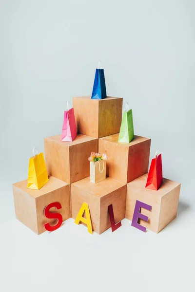 Vista ad alto angolo di borse colorate su supporti di legno con segno di vendita, concetto di vendita estiva — Foto stock