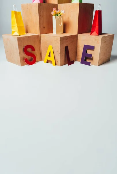 Цветные бумажные пакеты на деревянных стендах с табличкой продажи, концепция летней продажи — стоковое фото