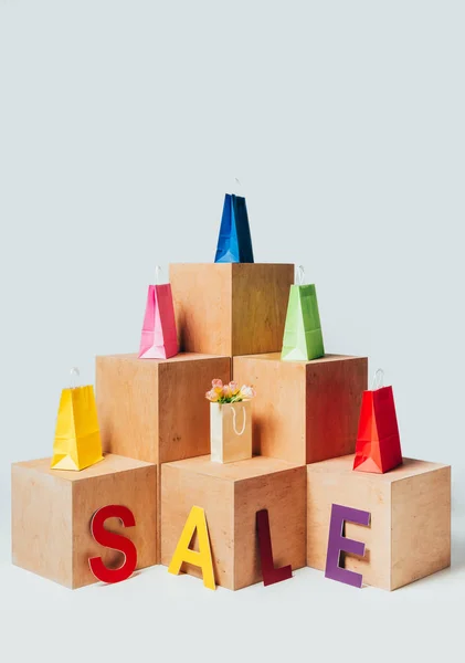 Sacos de compras coloridos em estandes de madeira com sinal de venda isolado no branco, conceito de venda de verão — Fotografia de Stock