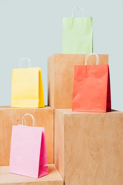 Цветные сумки для покупок на деревянных стендах, изолированные на белой, летней концепции продажи — стоковое фото