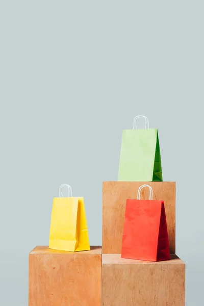 Três sacos de compras coloridos em estandes de madeira isolados em branco, conceito de venda de verão — Fotografia de Stock