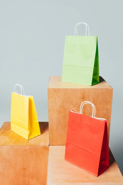 Three colored shopping bags on wooden stands, summer sale concept — Stock Photo