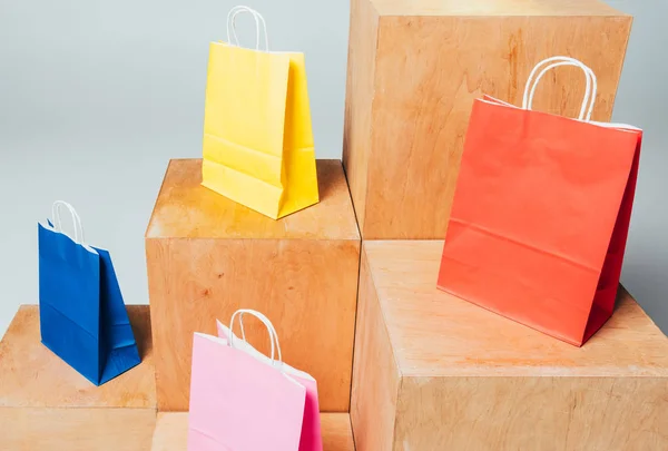 Bolsas de compras de colores en soportes de madera, concepto de venta de verano - foto de stock