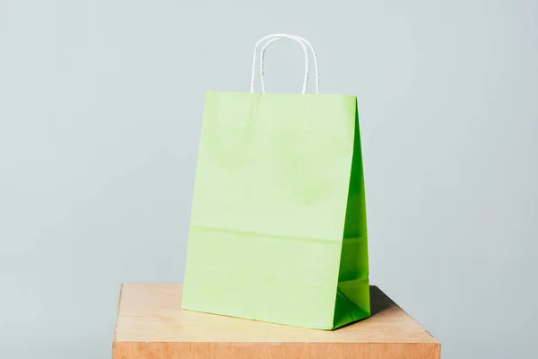 One light green shopping bag on wooden stand isolated on white, summer sale concept — Stock Photo
