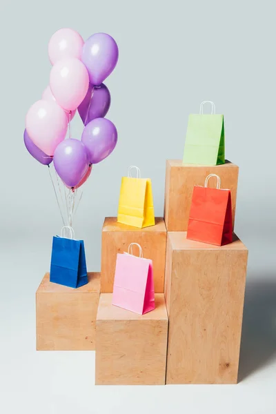 Paquet de ballons roses et violets près de sacs à provisions colorés sur les stands, concept de vente d'été — Photo de stock