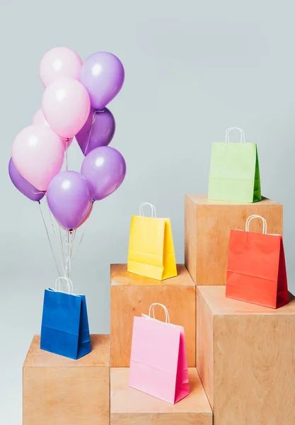 Fascio di palloncini rosa e viola vicino a sacchetti di carta su stand isolati su bianco, concetto di vendita estiva — Foto stock