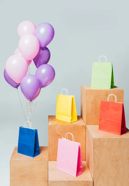 Bundle of pink and violet balloons near paper bags on stands isolated on white, summer sale concept — Stock Photo