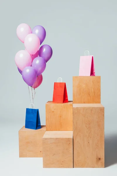 Paquet de ballons roses et violets près des sacs en papier sur les stands, concept de vente d'été — Photo de stock