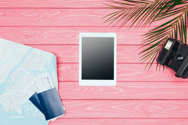 Top view of tablet surrounded with travel attributes on pink wooden surface — Stock Photo