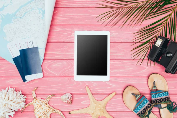 Vista superior do tablet cercado com vários atributos de viagem tropical na superfície de madeira rosa — Fotografia de Stock