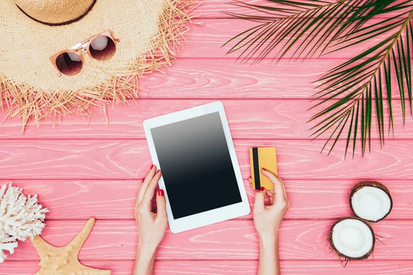 Tiro recortado de mulher segurando tablet digital com cartão de crédito na superfície de madeira rosa — Fotografia de Stock