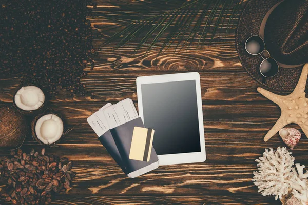 Top view of digital tablet and flight tickets surrounded with various tropical travel attributes on wooden surface — Stock Photo