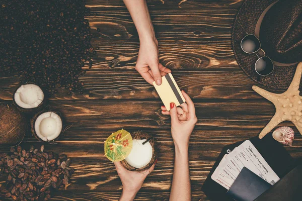 Cropped shot of woman paying for coconut cocktail with credit card on wooden surface — Stock Photo