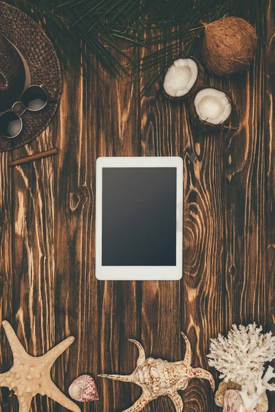 Vista superior do tablet digital na superfície de madeira cercada com vários atributos de viagem tropical — Fotografia de Stock